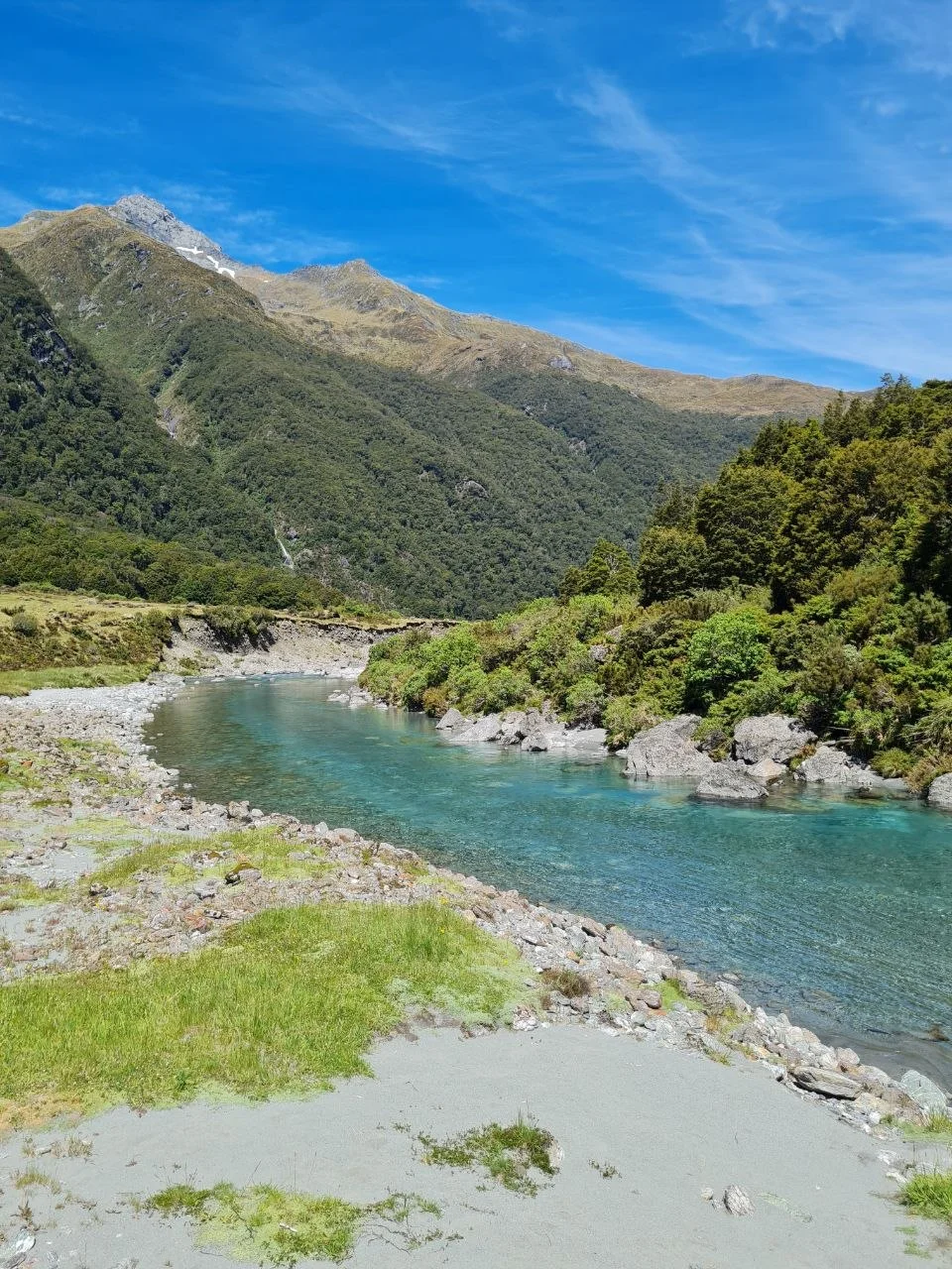 Turquoise river running through the Siberia Valley, dense beech forest on the slopes.