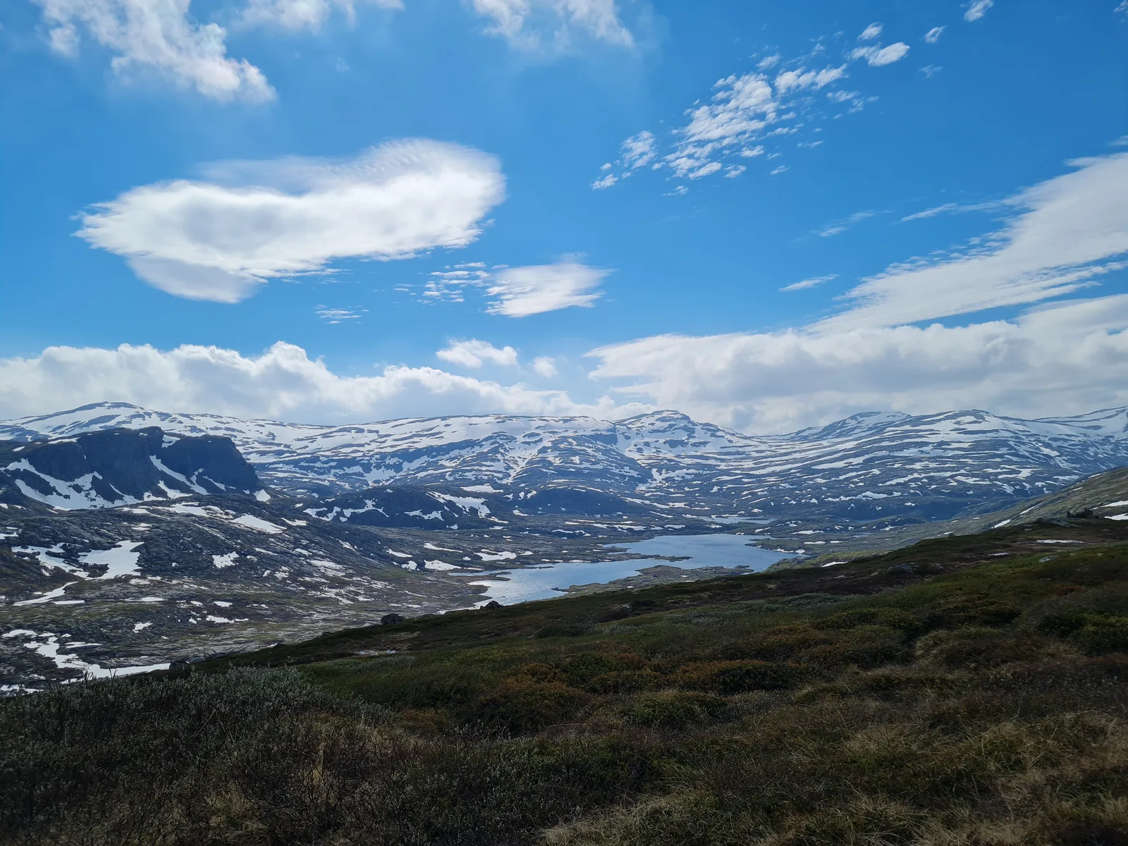 Expansive Hardangervidda fell panorama overlooking remote lakes and snow-dusted ridges in late afternoon light.