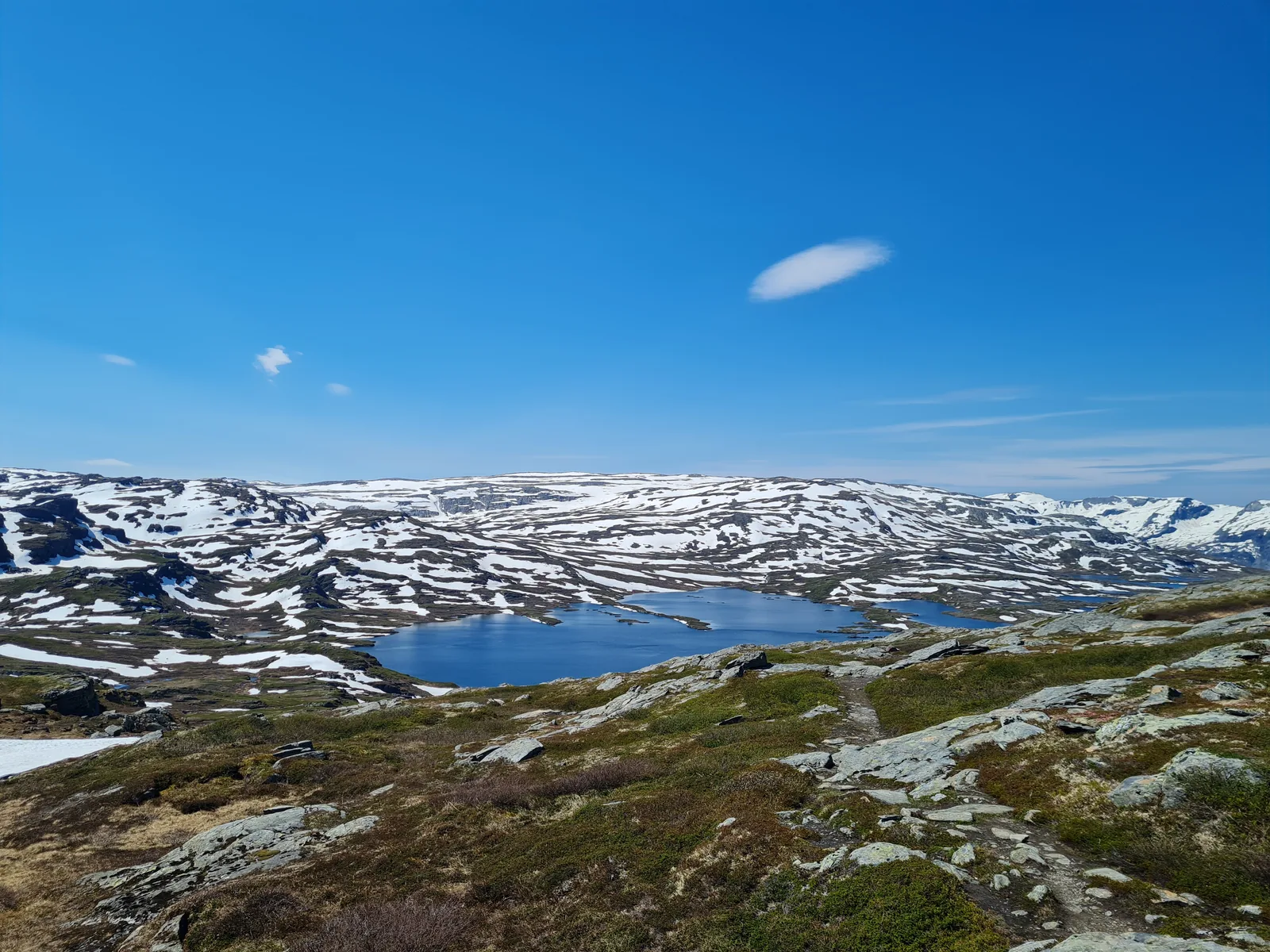Mountain trail traversing rocky slopes high above deep blue tarns on the western plateau.