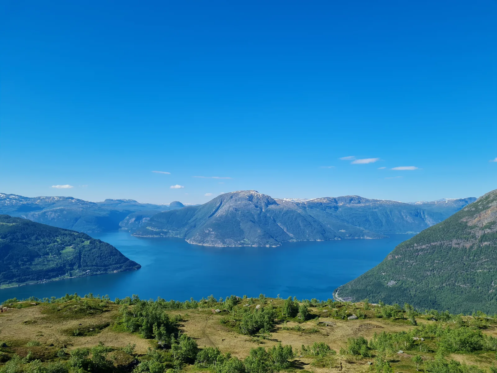 The iconic cliff-edge panorama from Dronningstien looking across the azure waters of Sørfjorden and Hardangerfjord.