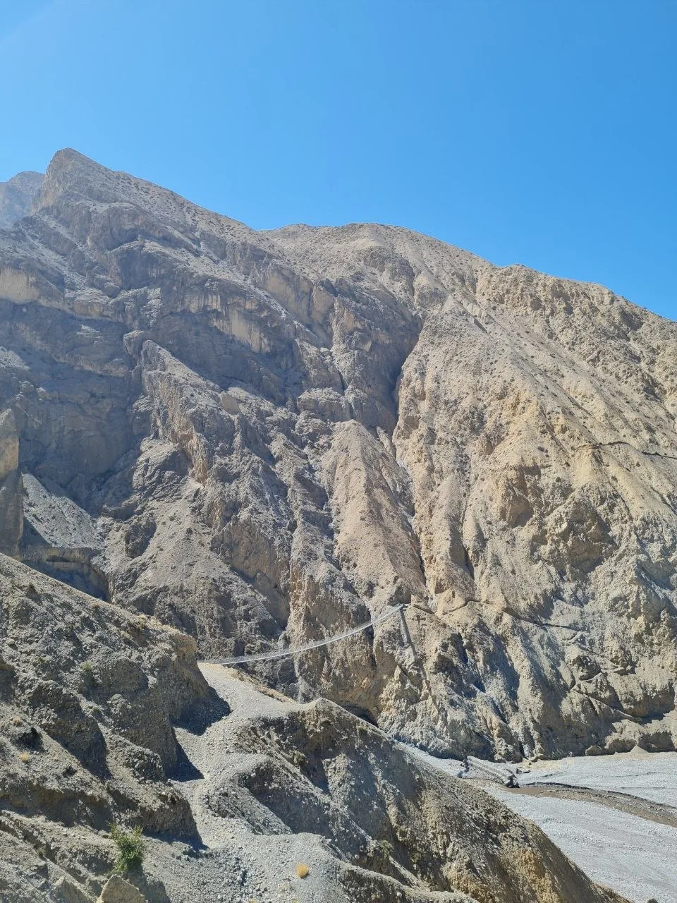 Eroded canyon walls and a narrow trail wind through the arid Mustang landscape.