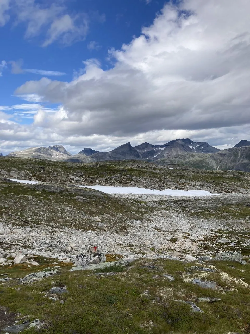 Mountain range under partly cloudy sky with rocky foreground