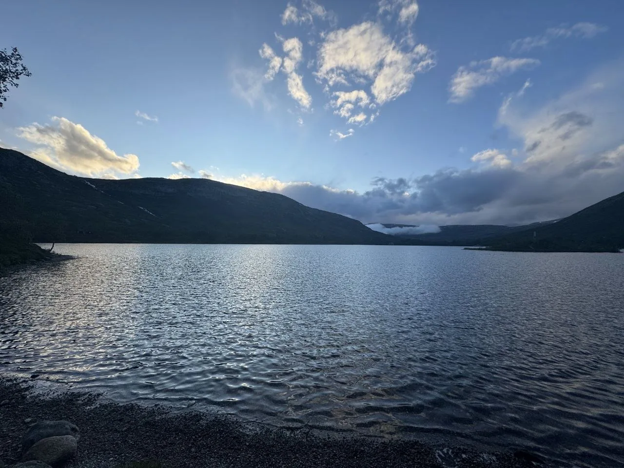 Evening view over calm lake with silhouetted mountain ridges