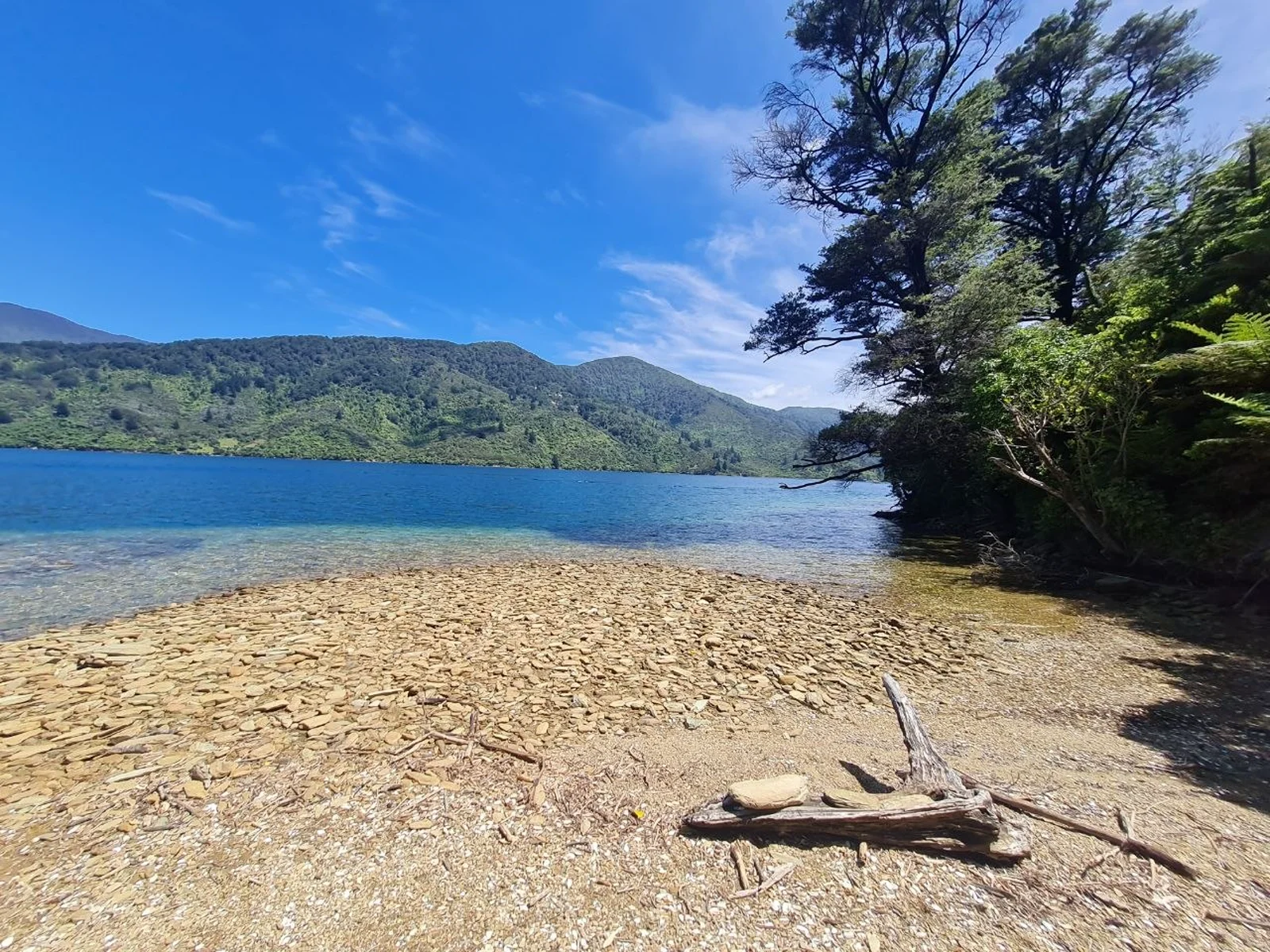 Tranquil bay with clear blue waters and pebbled shoreline