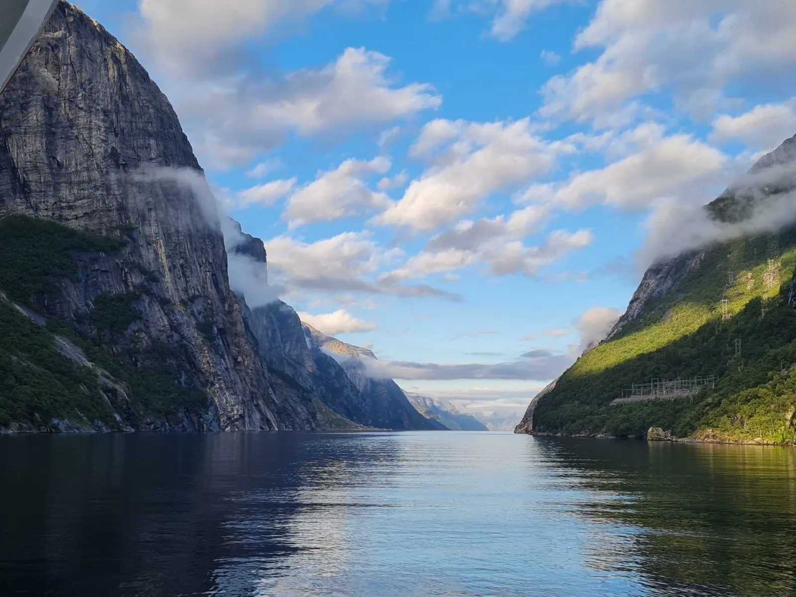The Lysefjord, sunlit and framed by dramatic cliffs with scattered clouds
