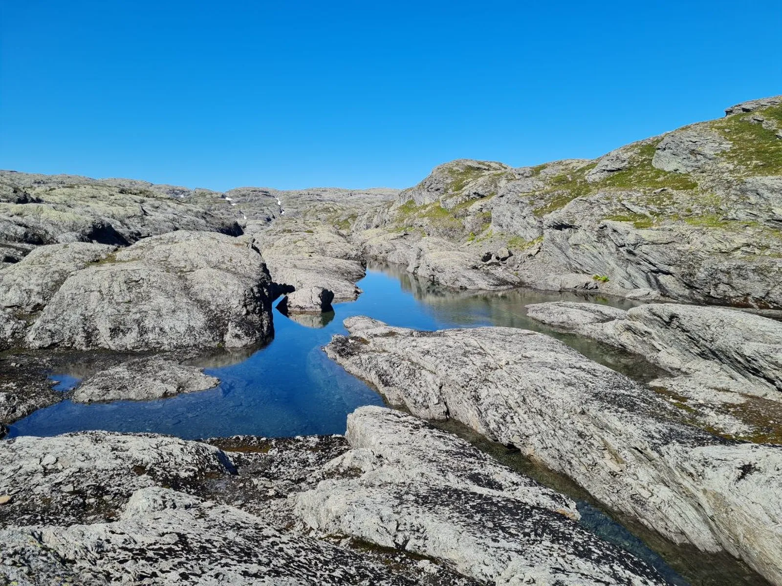 Clear blue pools reflect rocky highland terrain under a bright sky