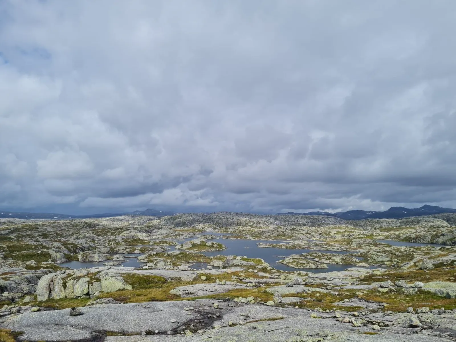Rocky mountain plateaus dotted with small ponds under a cloudy sky