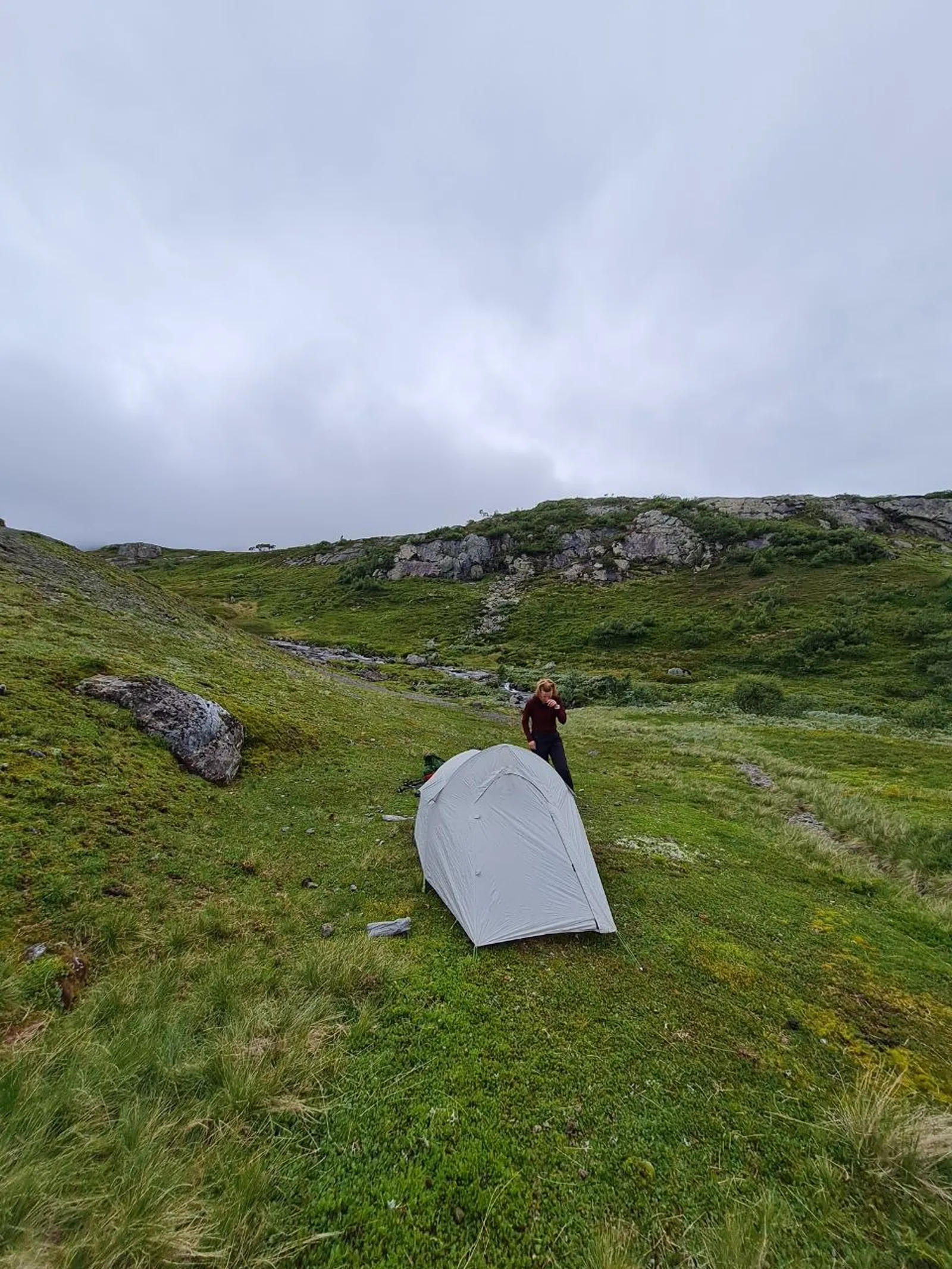 Tent pitched on lush green plateau beneath cloudy skies