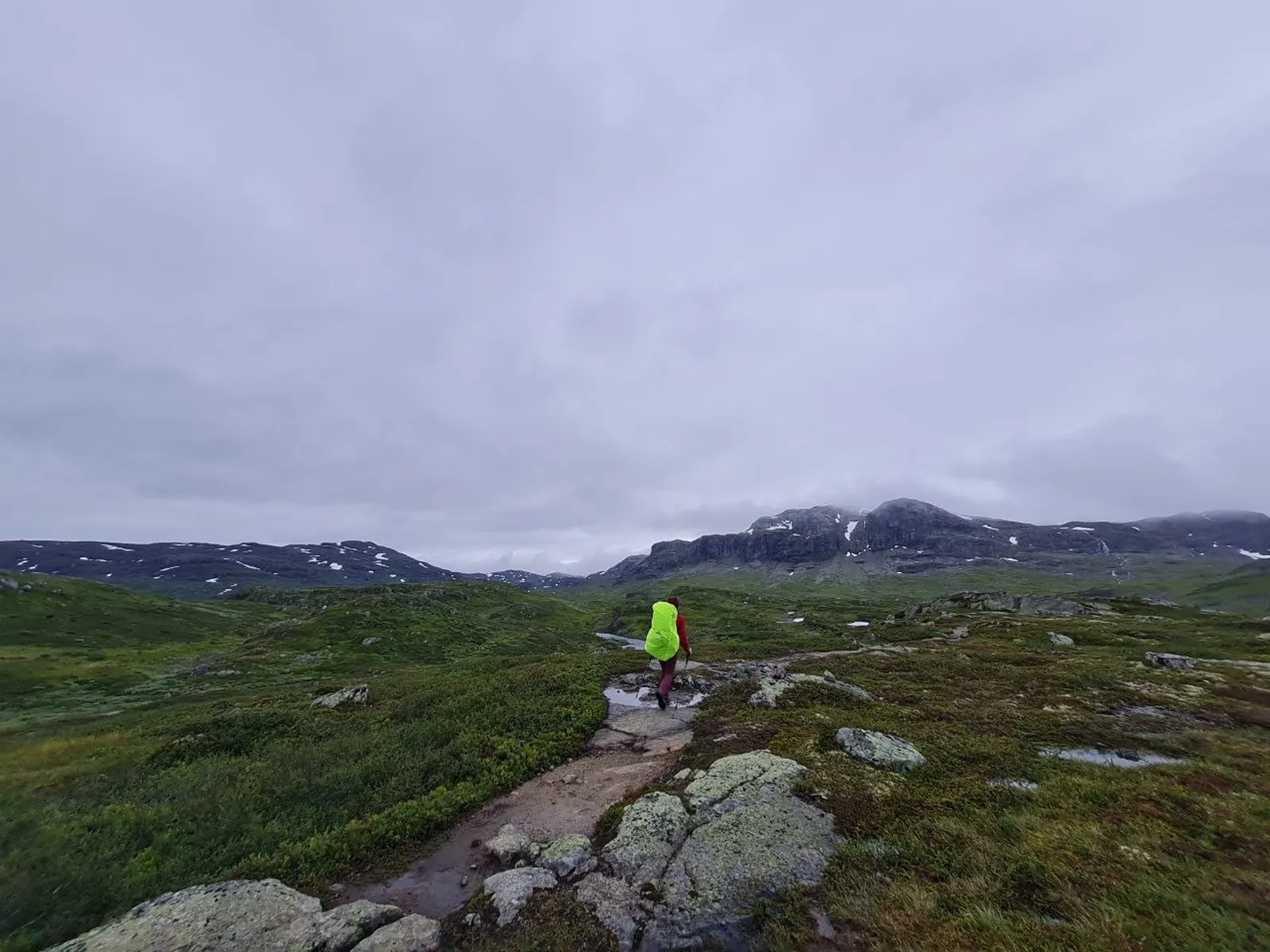 Hiker traverses rocky trail under overcast skies in Ryfylkeheiane mountains