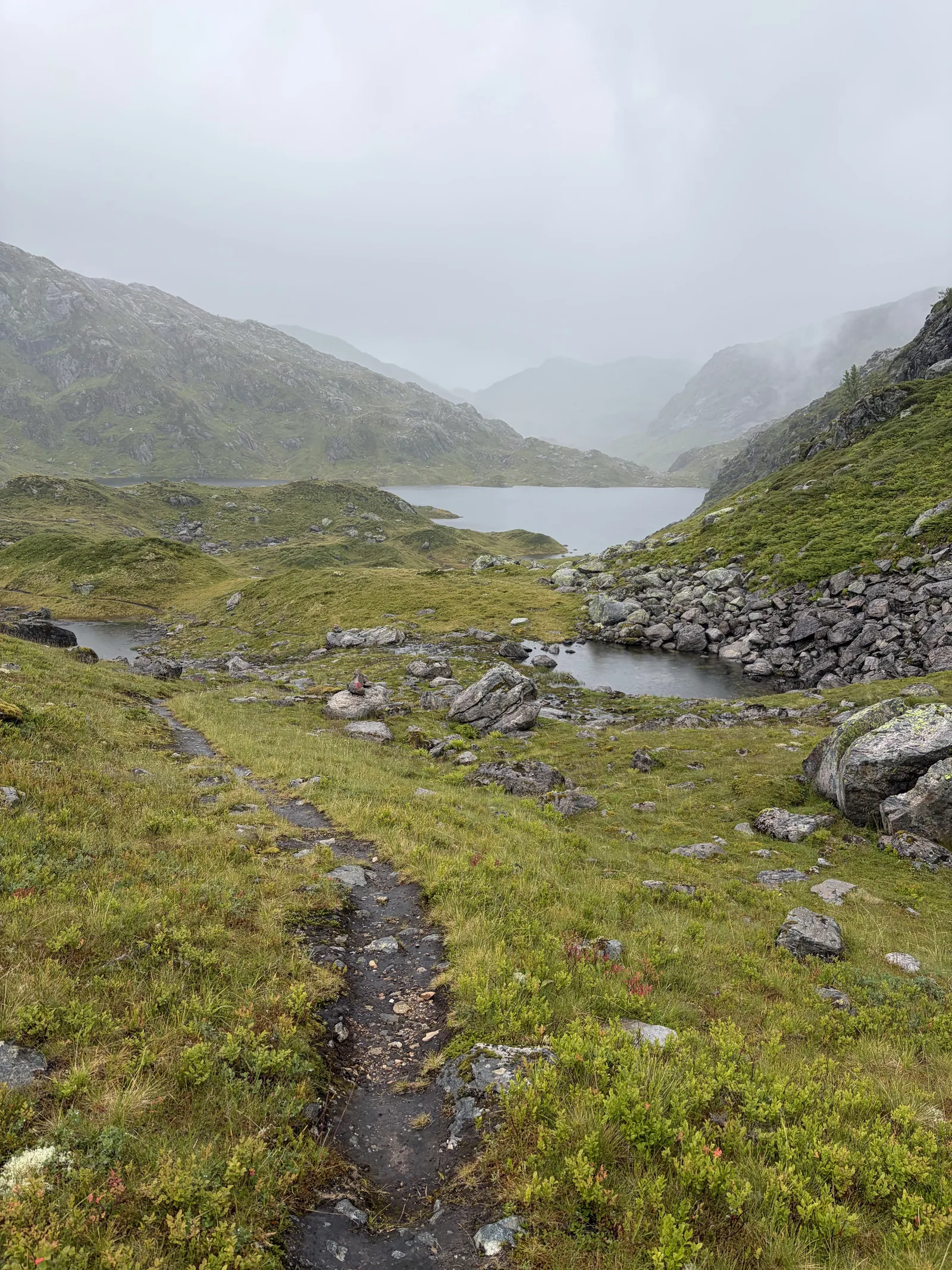 Ascending through the mist toward Skavlabu on Day 1, passing boulder-strewn terrain at 690 m above Mo i Modalen.