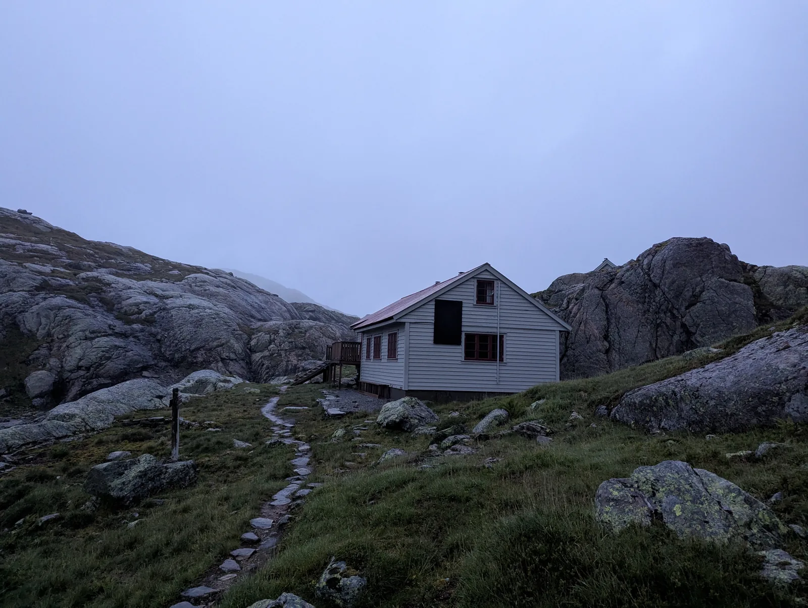 Norddalshytten cabin (1,009 m) nestled among glacial erratic boulders in the evening mist after Day 3.